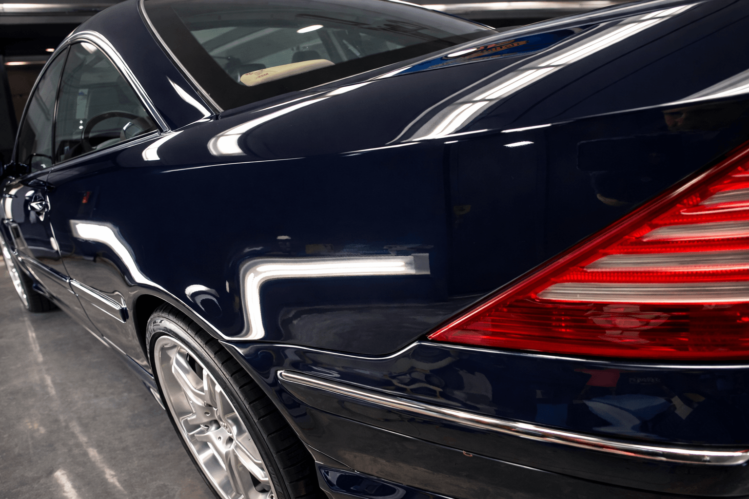 Blue sedan with sharp reflections after ceramic coating in garage bay