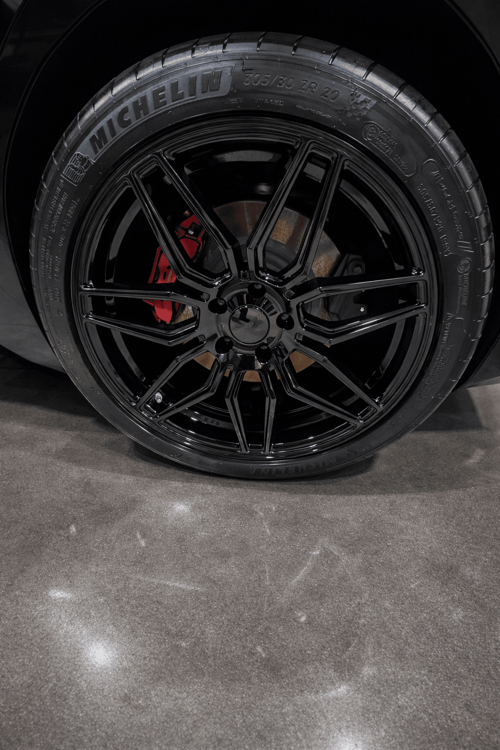 Glossy black wheel with red brake caliper after detailing