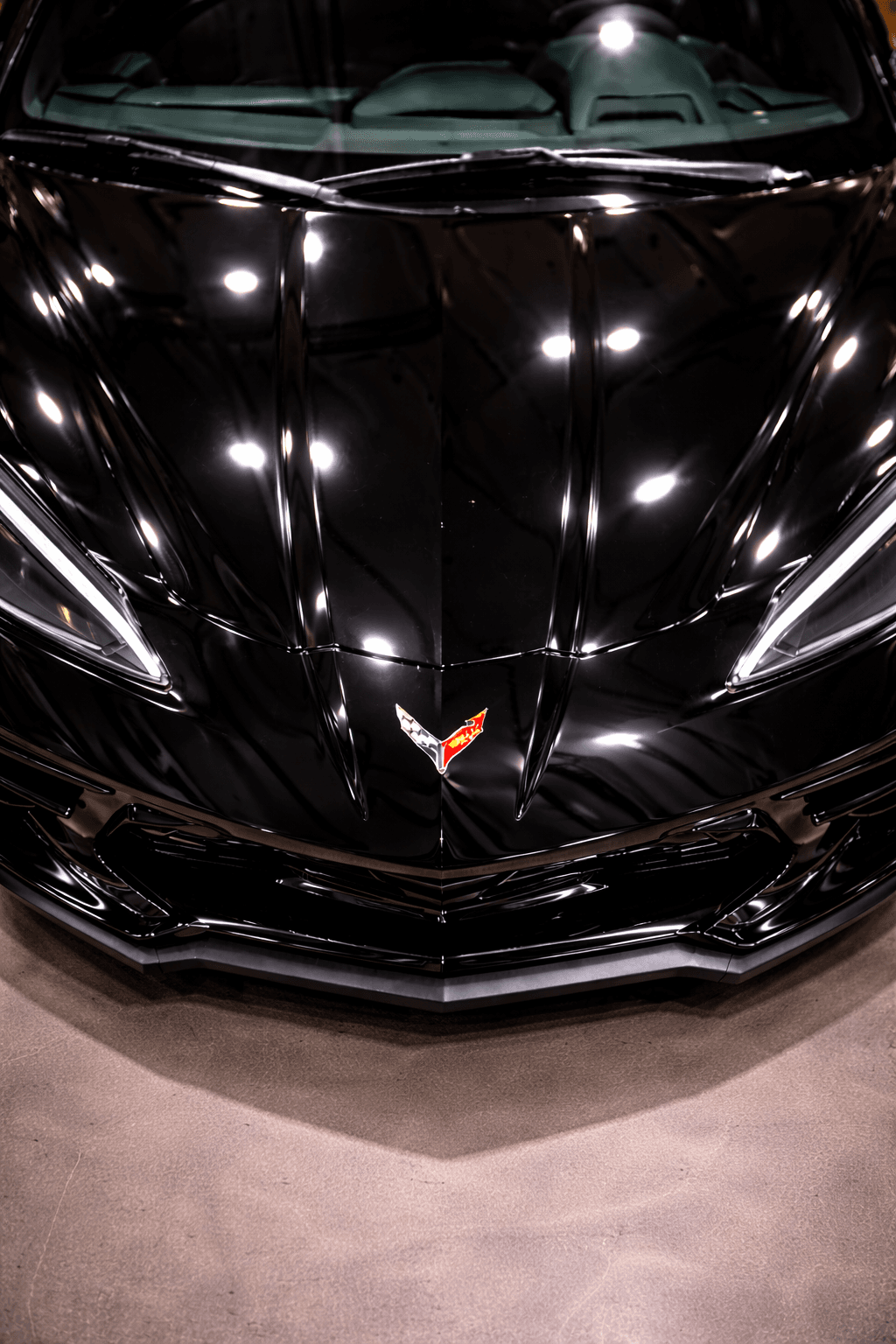 Black Corvette hood showing sharp reflections after correction